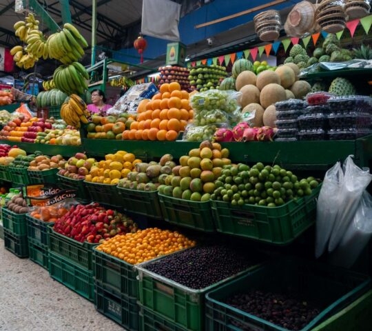 A fruit stall at a street market in Bogota, Colombia, with various colourful tropical fruits piled high in green crates