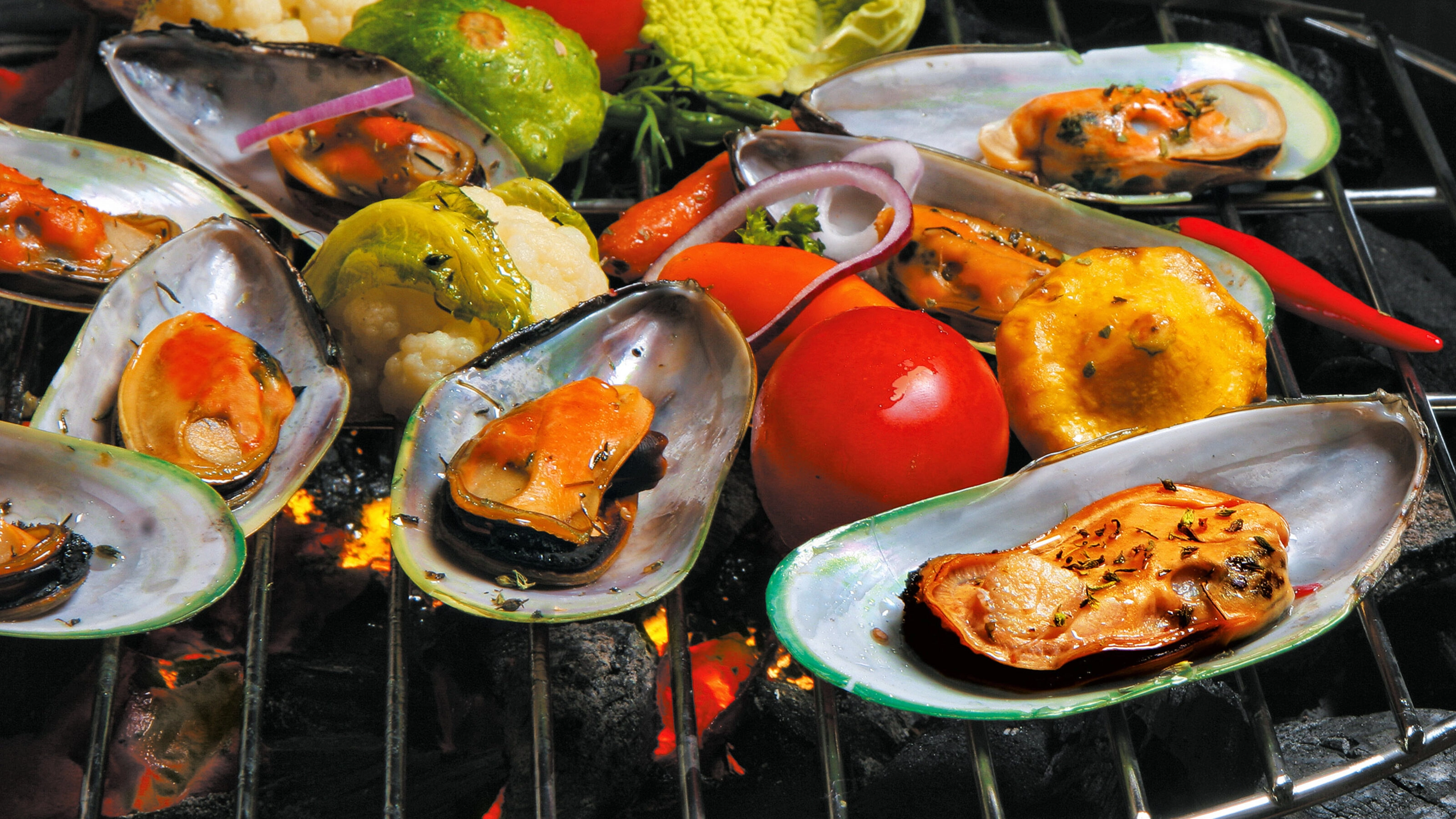 New Zealand Grilled Mussels with vegetables on the grill on a black background