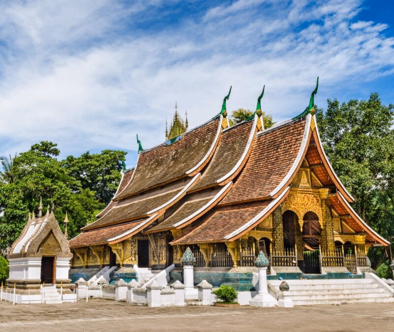 A traditional Laotian temple with a brown tiered roof and golden detail on luxury Asia grand tour holidays.