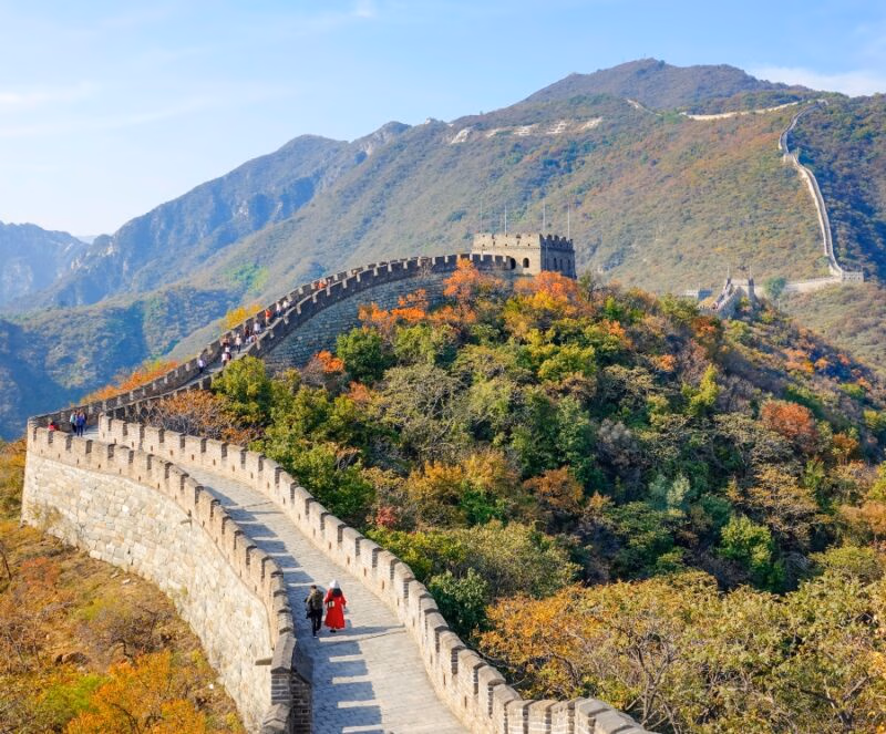 A view of the Great Wall of China surrounded by colorful fall trees on luxury Asia grand tour holidays.