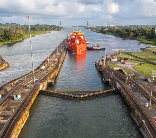 A view of an orange ship making its way down the Panama Canal
