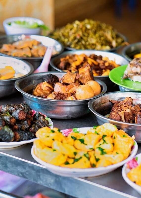 Various bowls of cooked meat, eggs, and vegetables arranged on a counter at a local food stall.