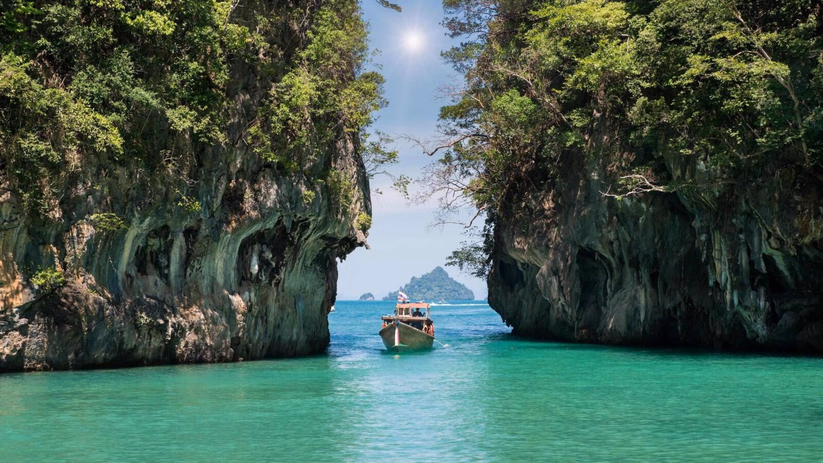 A boat sailing between two walls of rock in Phuket, Thailand