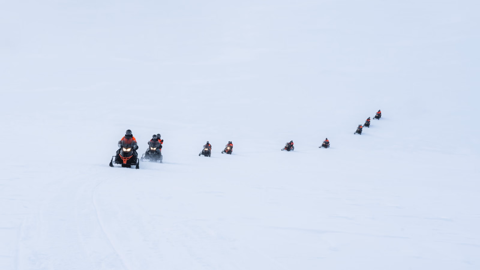 Group of tourists riding snowmobiles on snowy glacier mountain summit at Iceland