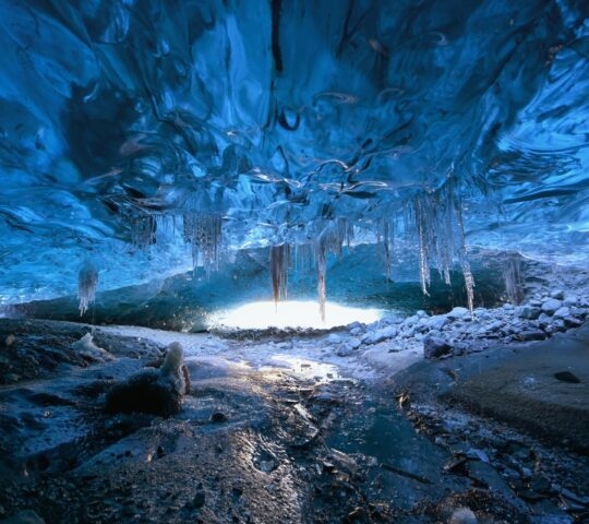 Photographer standing underground inside of a glacier, climate specific, vatnajokull National Park, amazing nature of Skaftafell, Entrance of an ice cave,Iceland