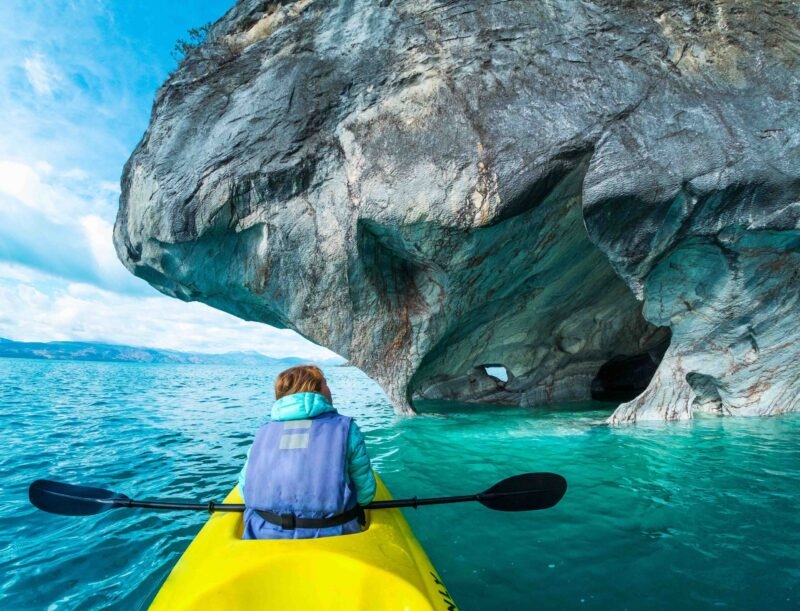 Woman sits in kayak and explores the Marble Caves and rocks on the lake of General Carrera, Chile