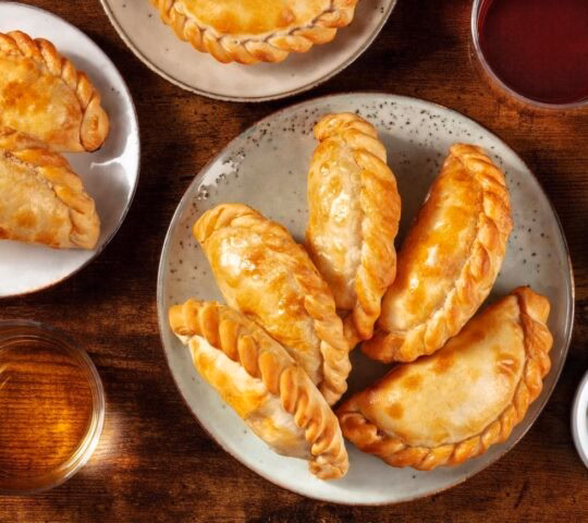 Many empanadas on a dark rustic wooden background