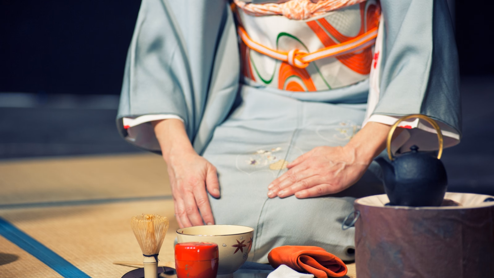 Japanese woman with light blue kimono holding a teacup, during the traditional tea ceremony