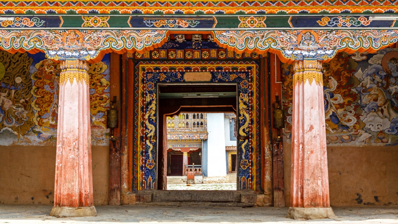 Ornate doorway of a traditional Bhutanese building with colorful carvings and paintings.