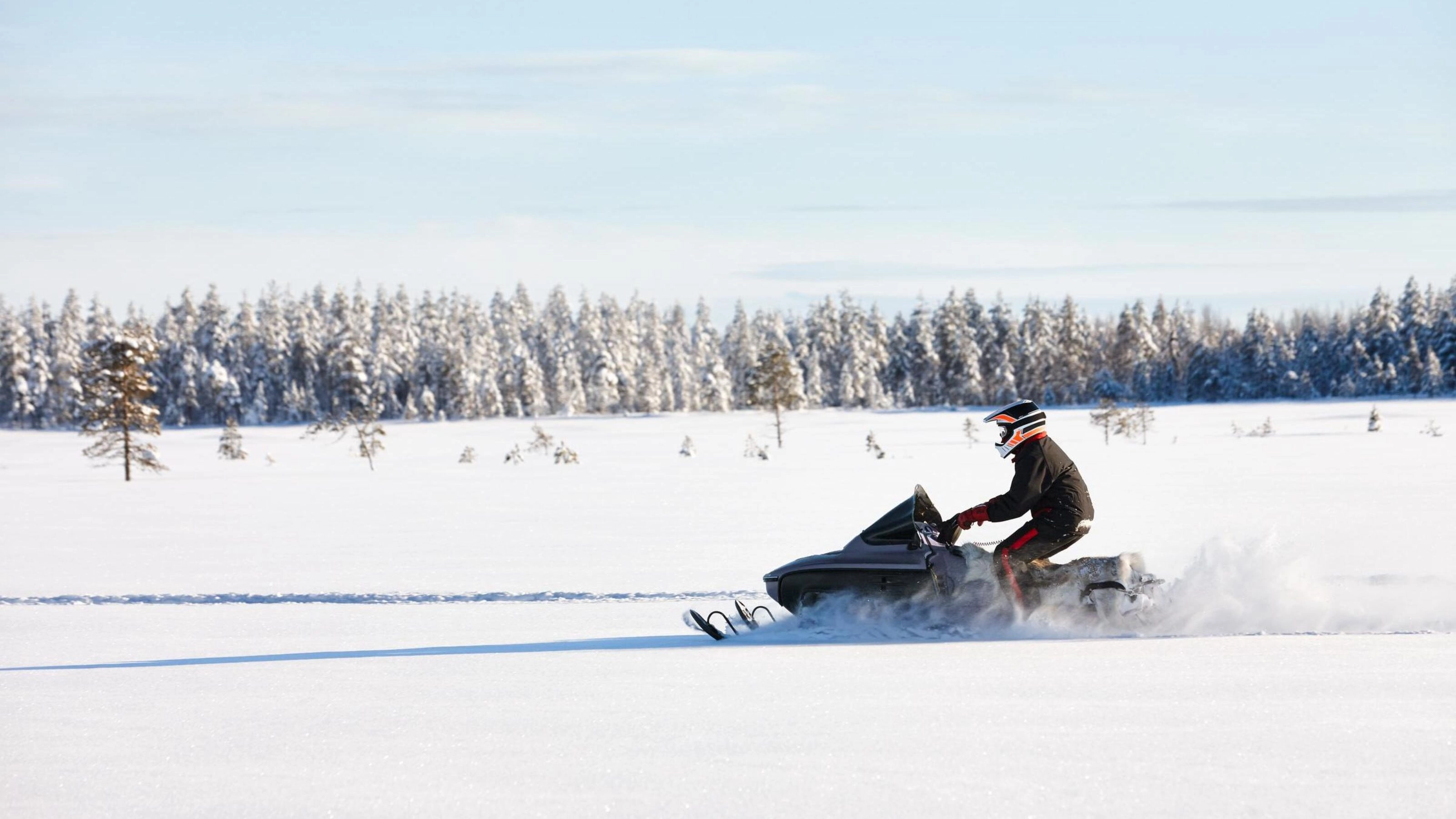 Man driving sports snowmobile in Finnish Lapland in a sunny day