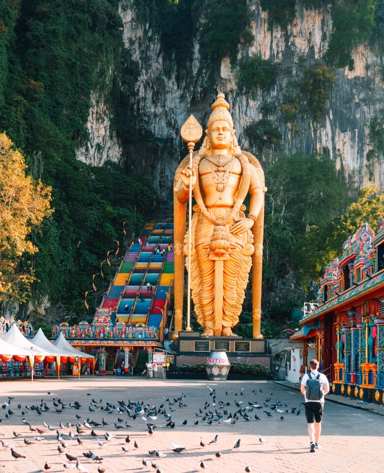 Giant gold Lord Murugan statue and colorful stairs at Batu Caves visited on luxury Malaysia trips.