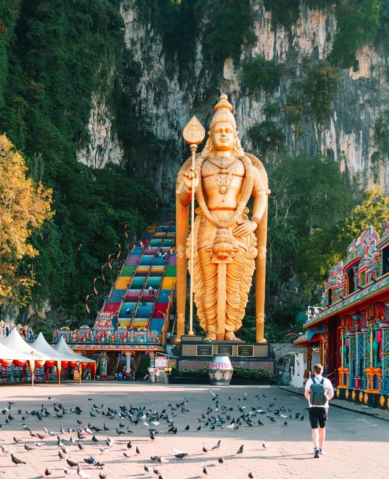 Giant gold Lord Murugan statue and colorful stairs at Batu Caves visited on luxury Malaysia trips.