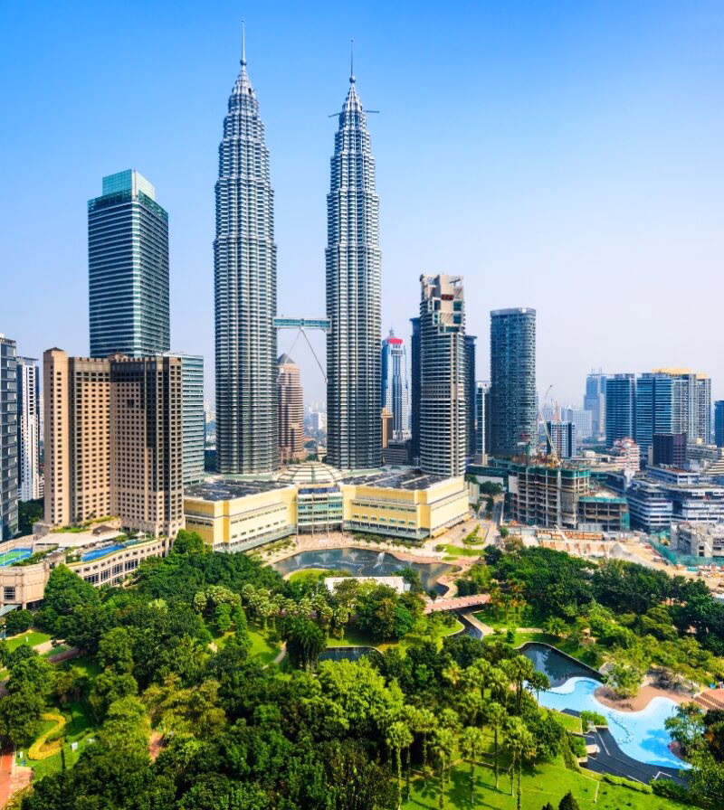 The Petronas Twin Towers loom over a lush city park and skyscrapers on luxury Malaysia trips.