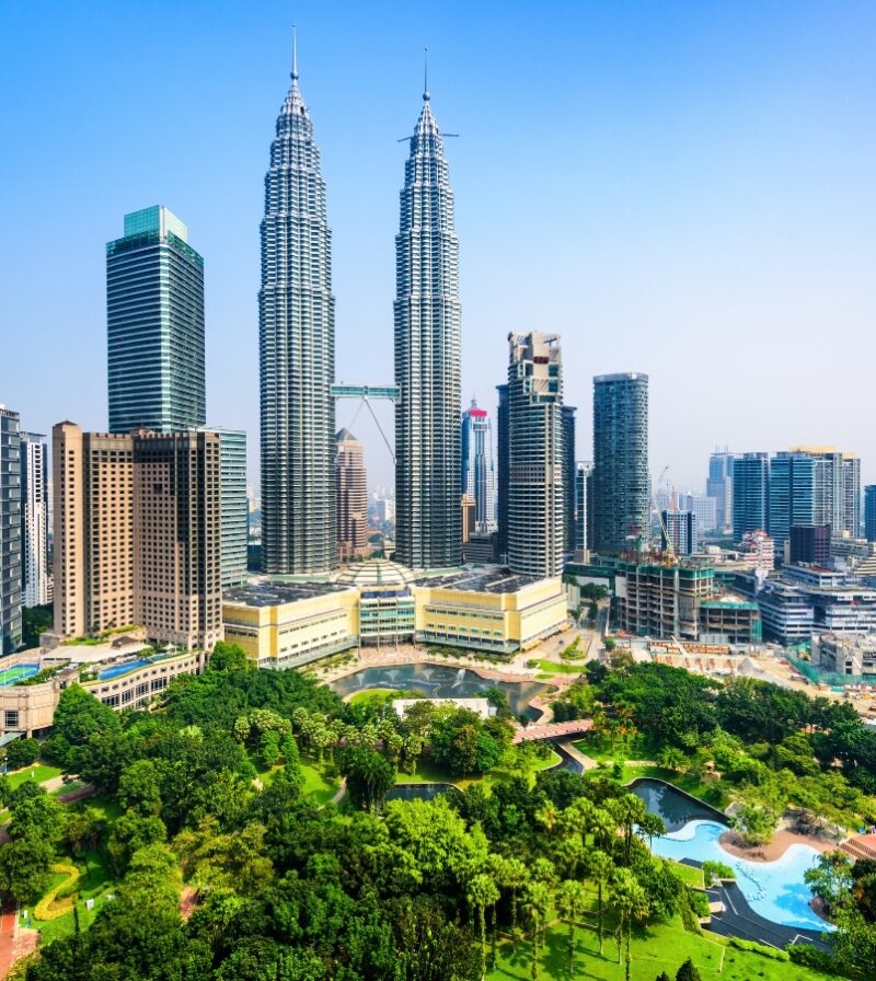The Petronas Twin Towers loom over a lush city park and skyscrapers on luxury Malaysia trips.