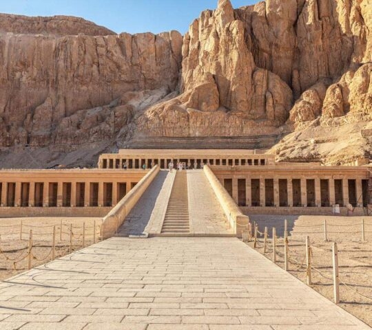 Ancient Egyptian temple facade with columns against a rocky desert backdrop.