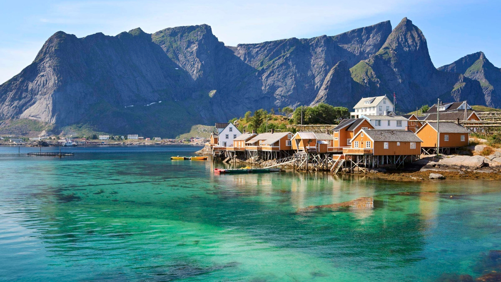 Scenic view of wooden houses along the coastline with mountains in the background.