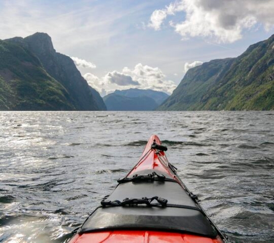 View from a kayak on a lake with mountain scenery in the background.