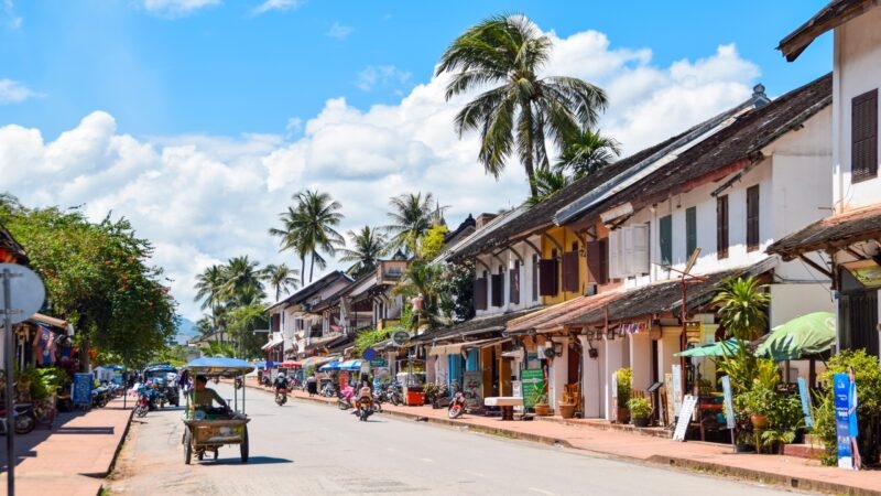 A vibrant street lined with traditional houses under a sunny blue sky.
