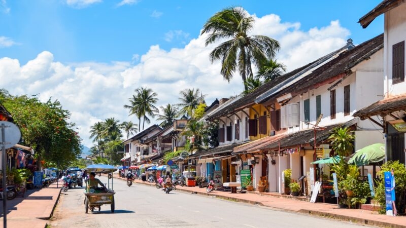 A vibrant street lined with traditional houses under a sunny blue sky.