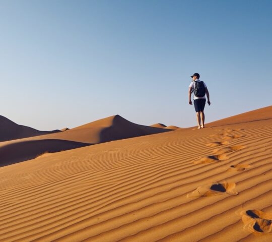 A man hiking through sand dunes in the Omani desert