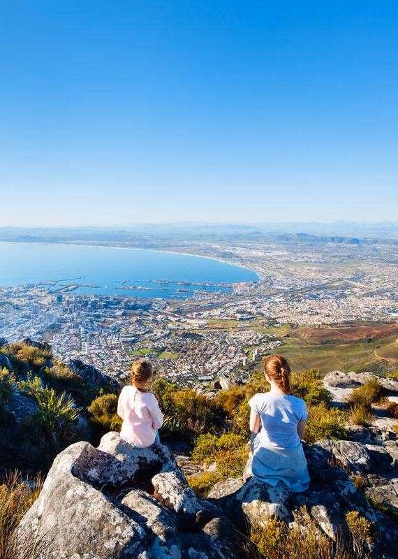A person hiking through a rocky landscape at sunset during luxury Cape Town holidays.