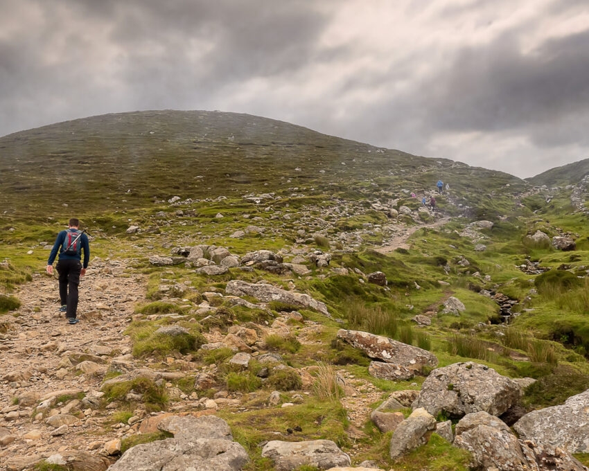 Foot path to the top of Croagh Patrick and one tourist. Low clouds over mountains peak, travel and explore Ireland concept