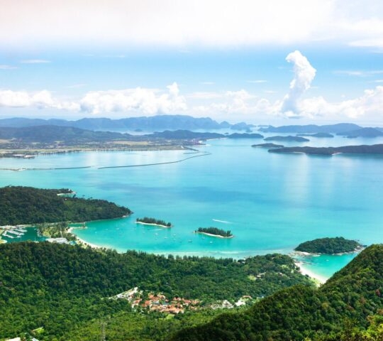 Aerial view of a tropical coastline with turquoise waters, islands, and a lush green landscape.
