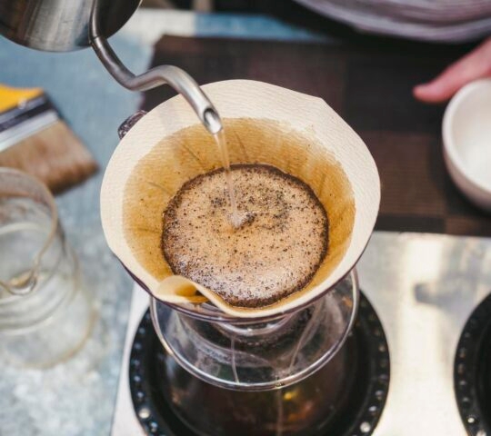 Pouring hot water over coffee grounds in a filter for drip brewing.