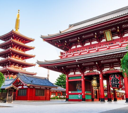 Bright red Japanese temple gate with a large lantern and a tall five-story pagoda.