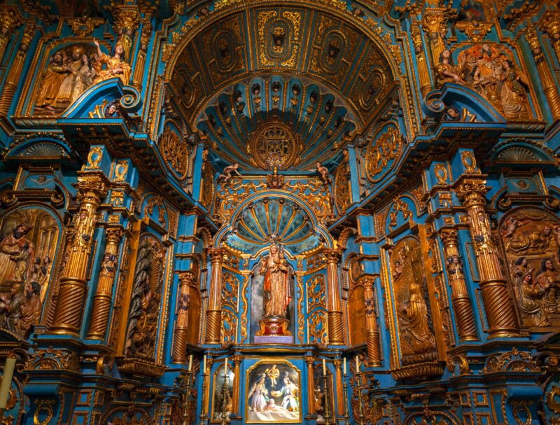 Ornate blue and gold baroque church altar with sculptures and religious art.