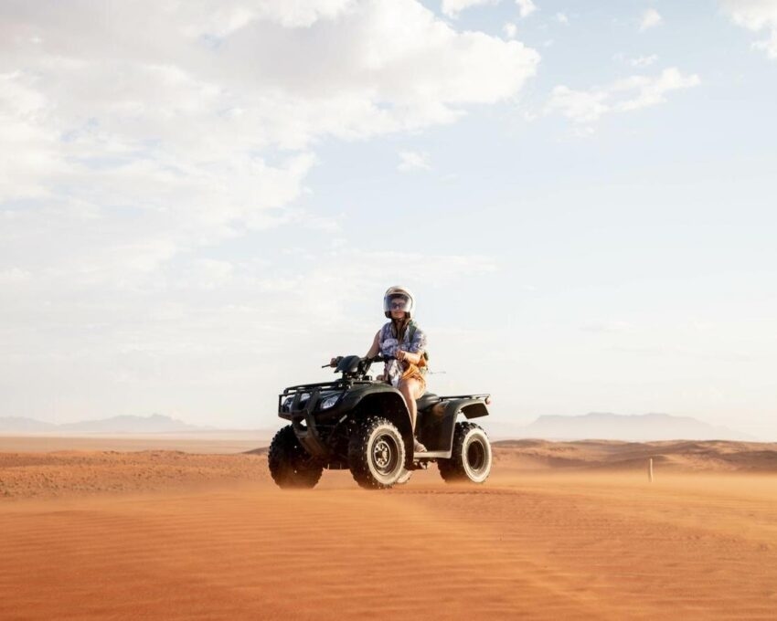 A person riding a quadbike through the sand dunes at Sossusvlei, Namibia