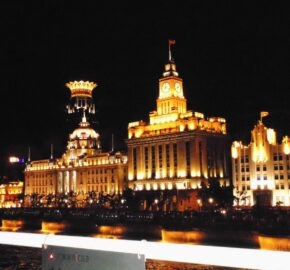 Historic illuminated buildings at night by waterfront.