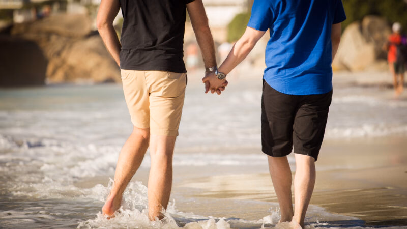 Two people holding hands and walking on a sandy beach during luxury Africa honeymoon holidays.