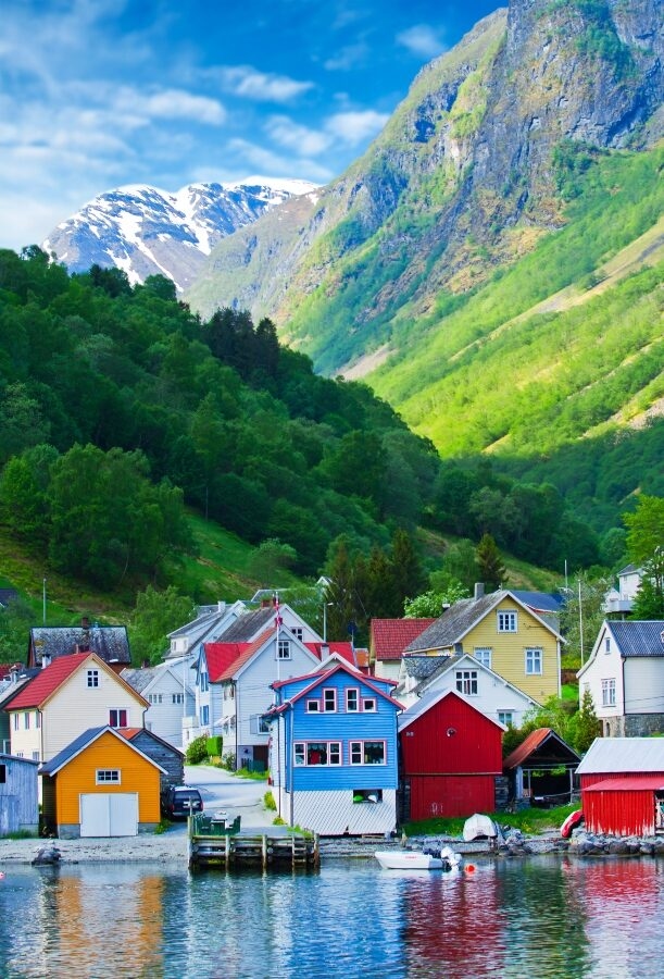Colorful houses by a fjord with mountains in the background.