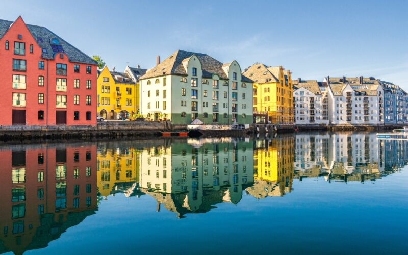 Colorful buildings reflecting in water under a clear blue sky.