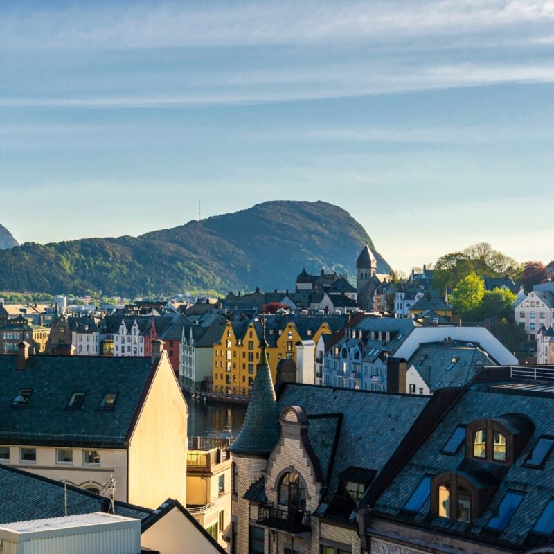 Cityscape with colorful buildings and a mountain backdrop during sunset.