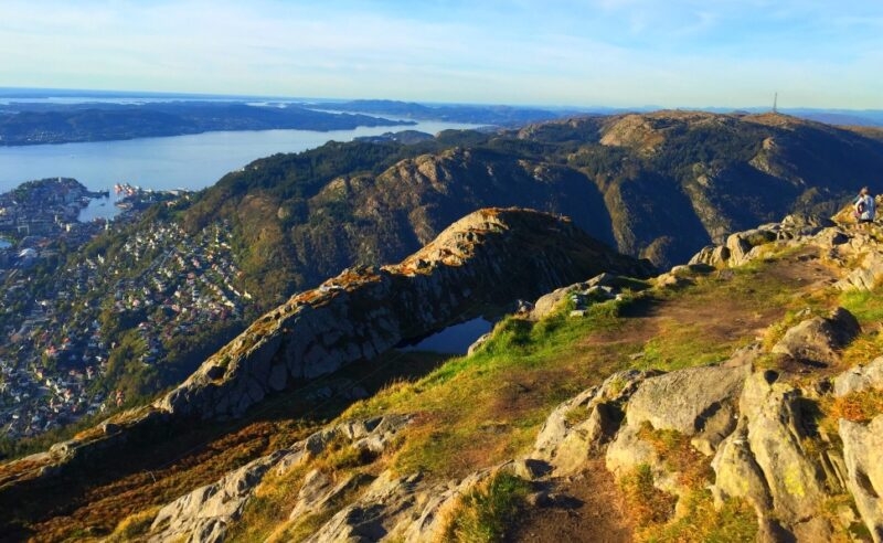 Mountainous landscape overlooking a town with waterways and distant hills under clear skies.