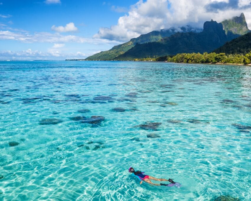Luxury travel vacation tourist woman snorkeling in Tahiti ocean, Moorea island, French Polynesia.