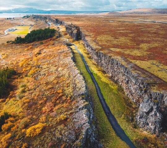 Aerial view of a road splitting through a colorful, rocky landscape with autumn foliage.