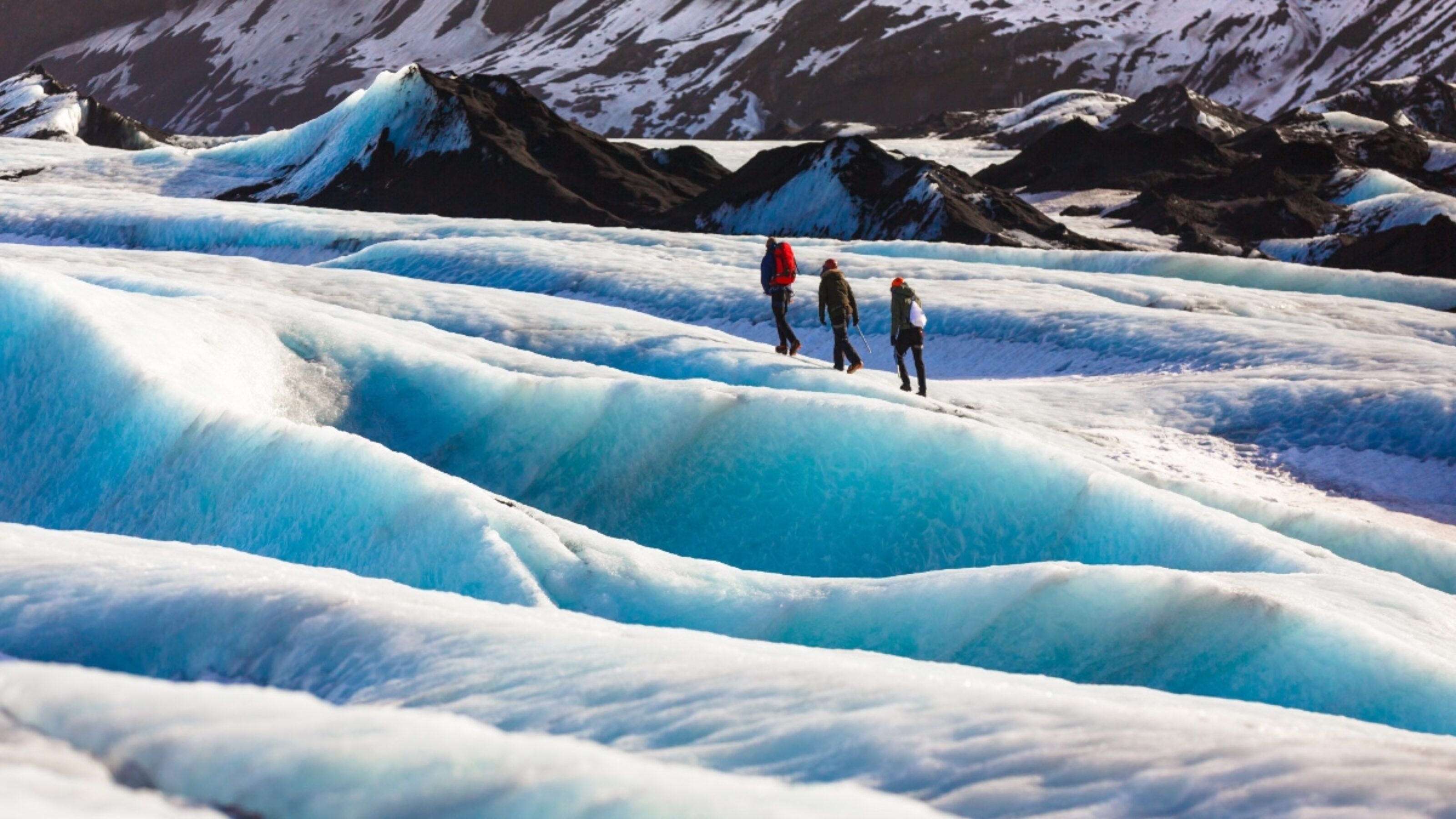 Private guide and couple of hiker walking on glacier at Solheimajokull, Iceland