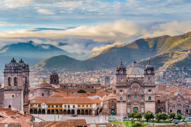 Cusco's historic center with colonial architecture and mountainous backdrop at dusk.