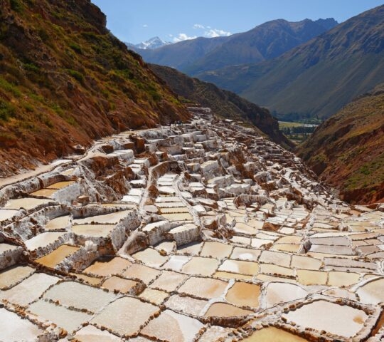 Terraced salt pans in a mountain valley with clear skies.