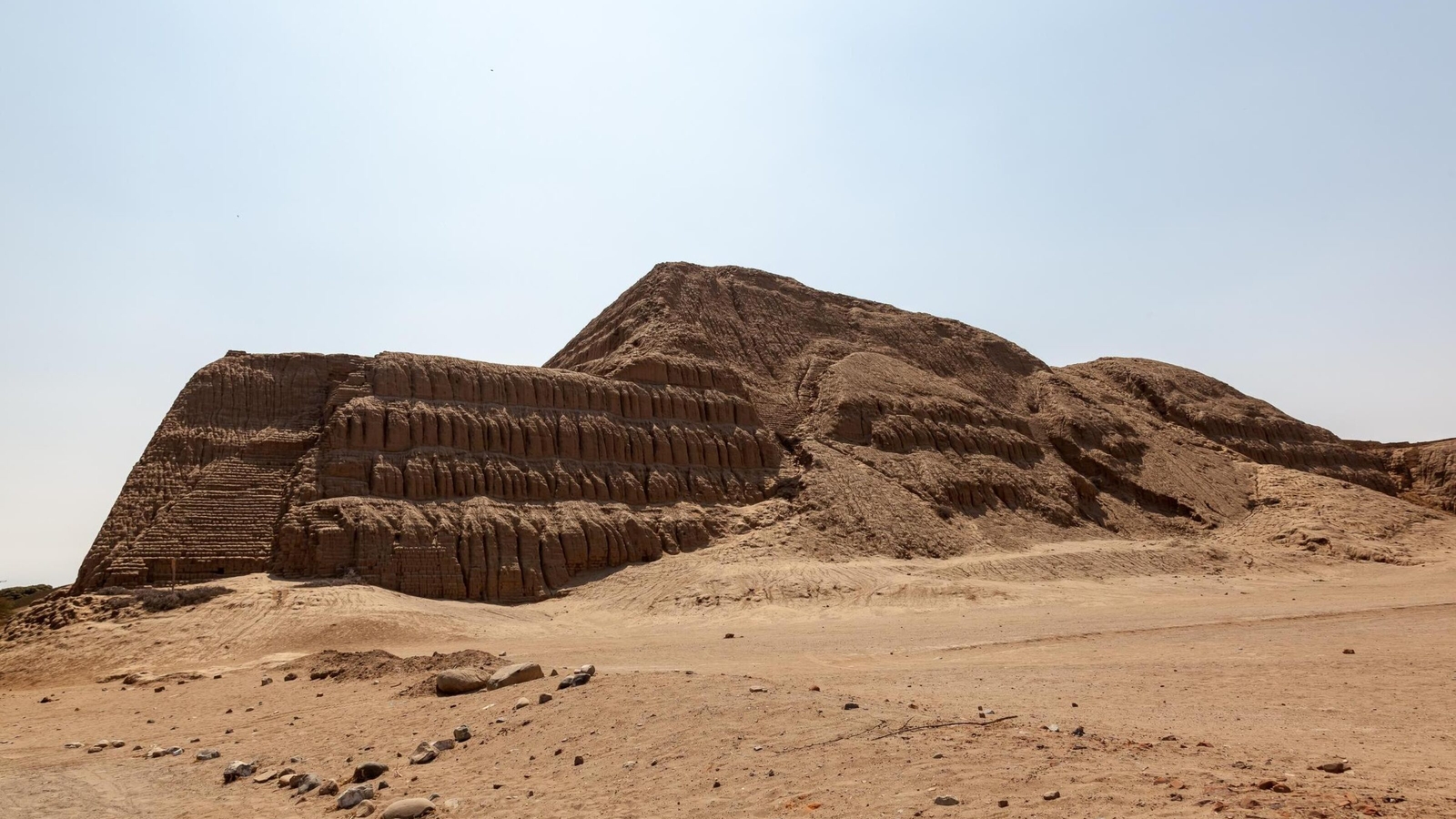 Ancient step pyramid structure in a desert landscape under a clear sky.