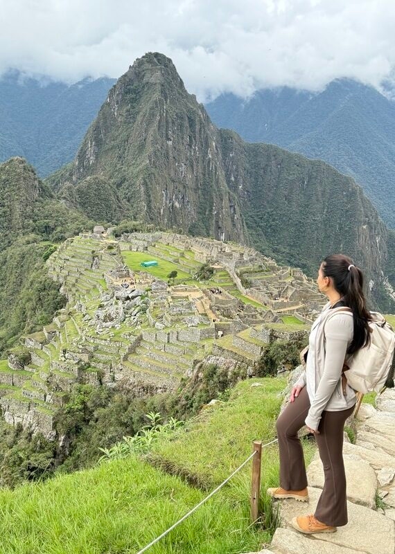 A person admiring the ancient Machu Picchu ruins amidst mountainous terrain.
