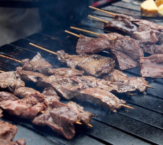 Anticuchos being cooked over a grill in Peru
