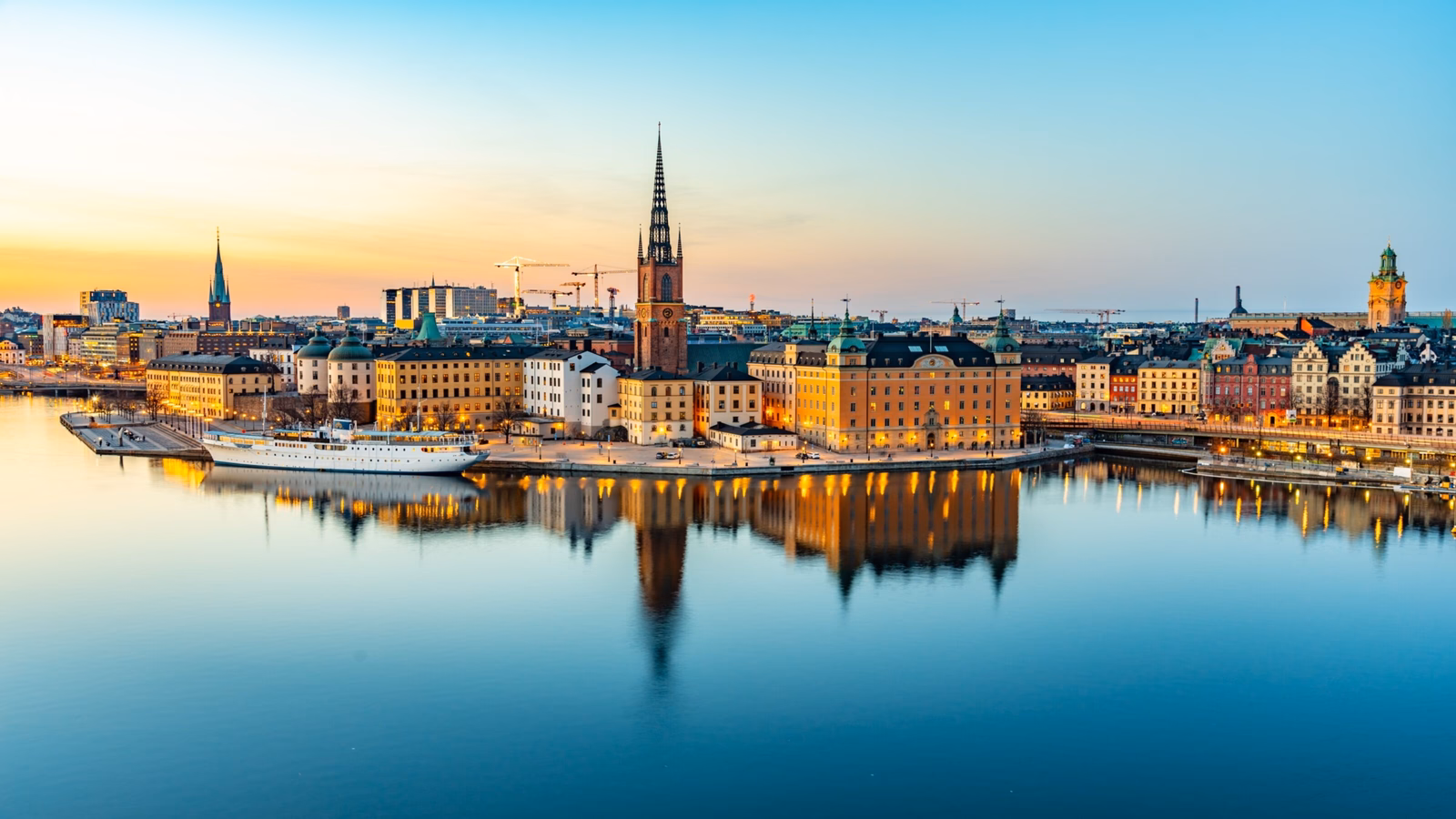 Twilight cityscape with historic buildings reflected in calm water.
