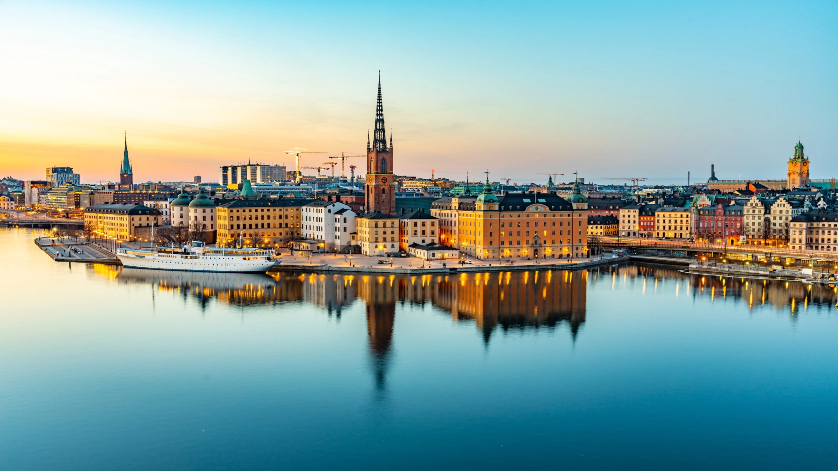 Twilight cityscape with historic buildings reflected in calm water.