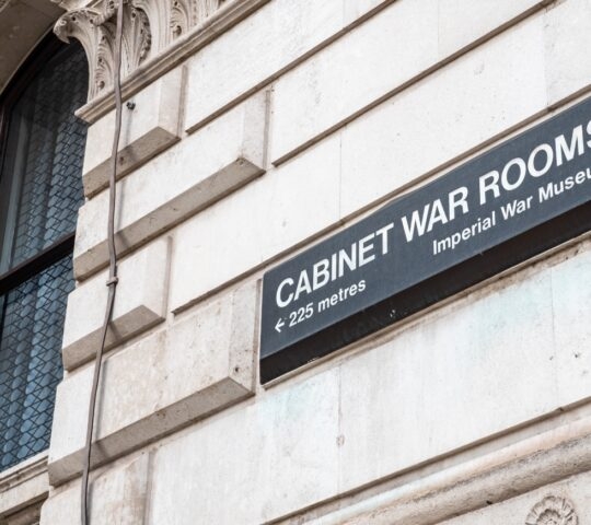 Sign on a building indicating "CABINET WAR ROOMS" with direction arrow and distance "less than 225 metres."