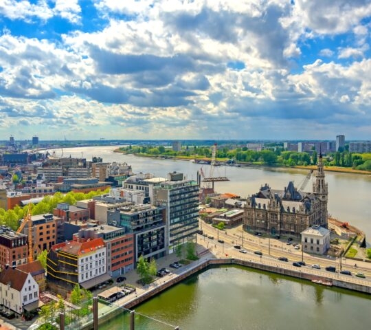 A panoramic cityscape with a river, ornate buildings, and a cloudy sky.