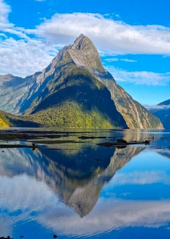 Mountain peak reflecting on a calm lake with clear blue skies.